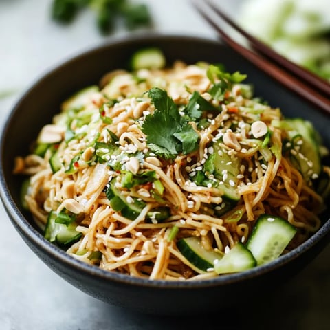 A bowl of noodles with vegetables and herbs.