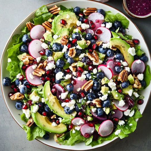 A plate of food with blueberries, avocado, and lettuce.