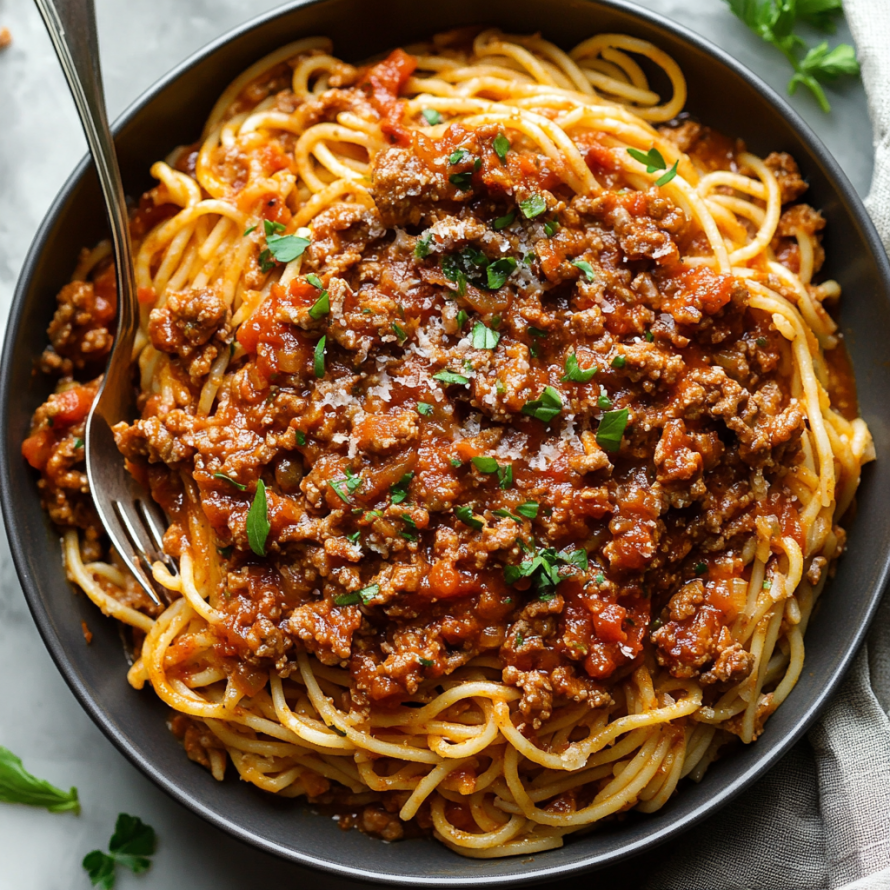 A bowl of spaghetti with meat sauce and green herbs.