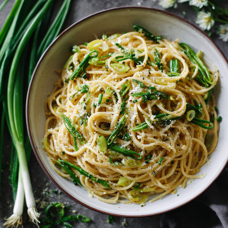 A bowl of Lemon Garlic Scape Pasta with a fork and a knife nearby.