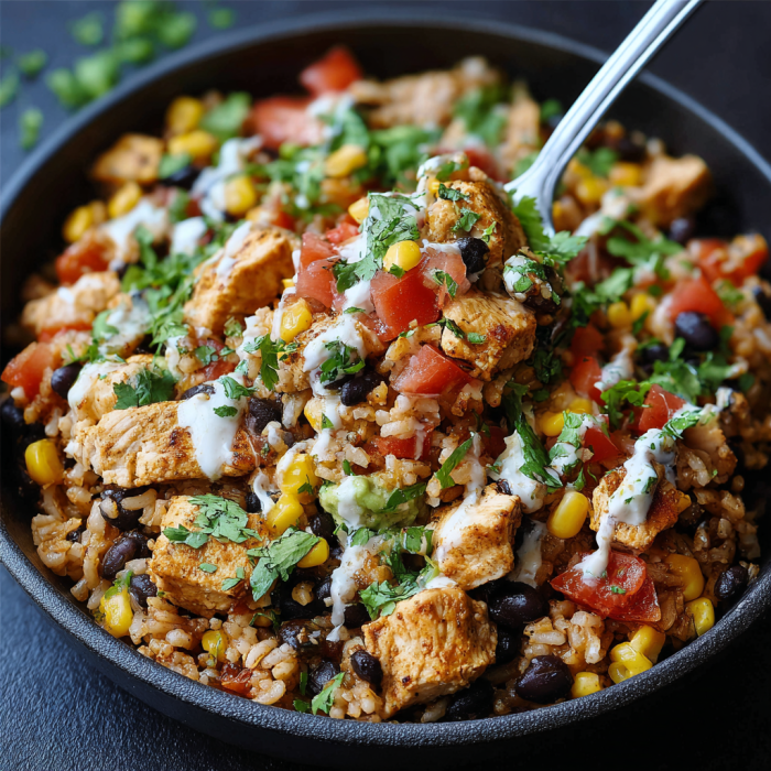 A bowl of rice and beans with chicken and tomatoes, topped with white sauce.
