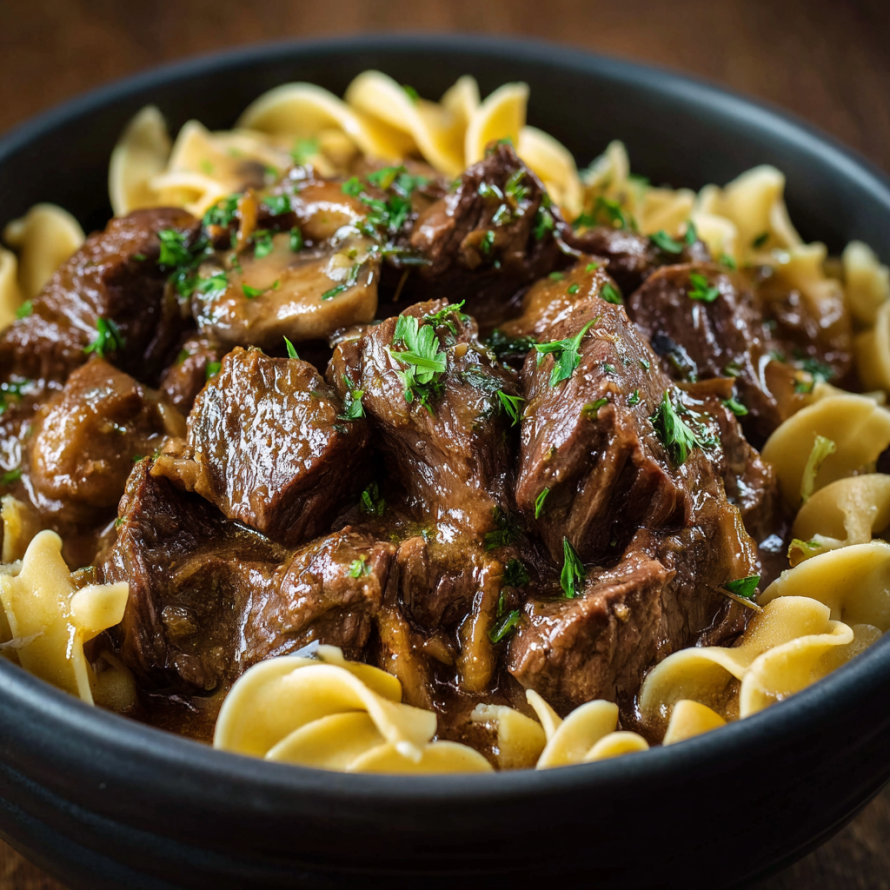 A bowl of beef stew with pasta and mushrooms.