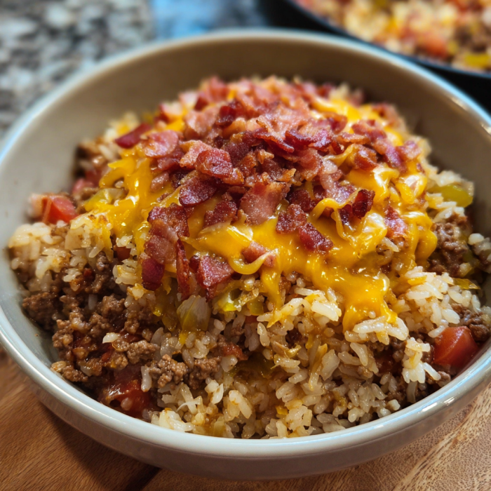 A bowl of rice with bacon and cheese on top.