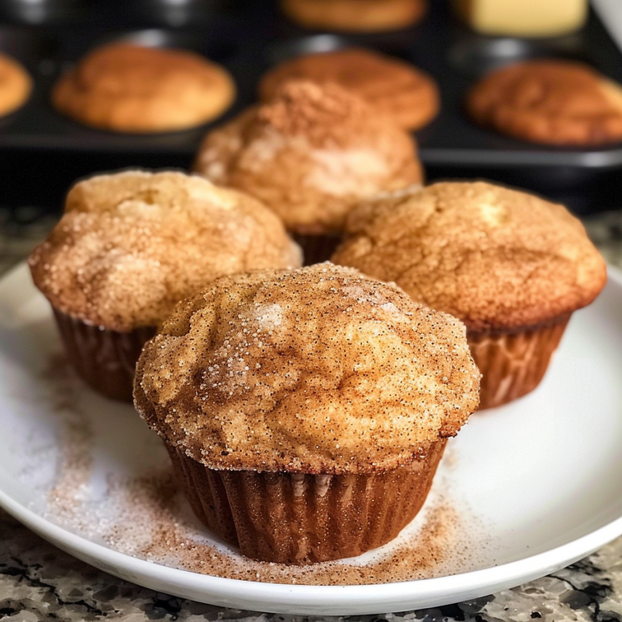 A plate of Snickerdoodle Muffins with a dusting of powdered sugar.