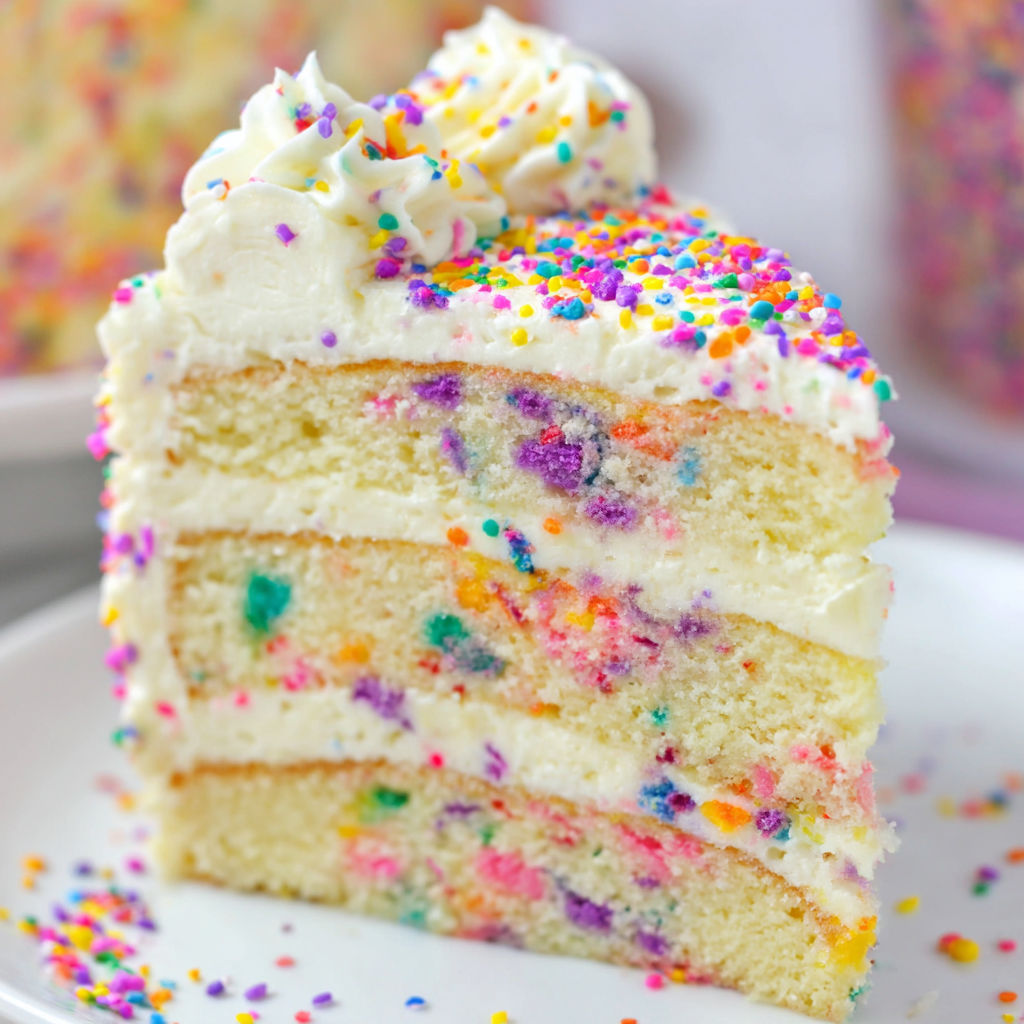 A slice of cake with colorful sprinkles on a plate.