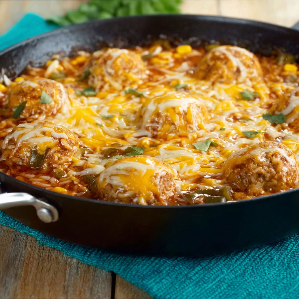 A pan of chili with meatballs and cheese on a table.