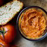 A glass bowl of red sauce with a loaf of bread.