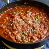 A bowl of chili with meat and cheese.