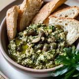 A bowl of Green Olive Tapenade with bread and a green vegetable.