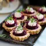 A tray of beetroot tartlets with goat cheese on a table.