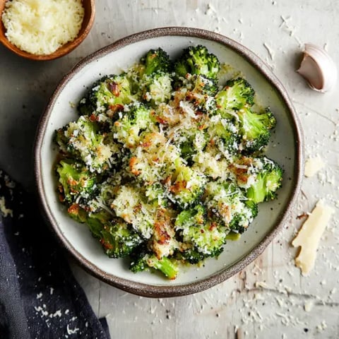 A bowl of broccoli with cheese and spices.
