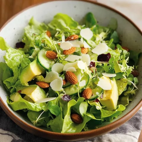 A bowl of salad with lettuce, cucumber, and almonds.