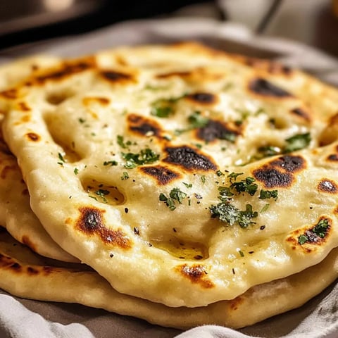 A stack of tortillas with green herbs on top.