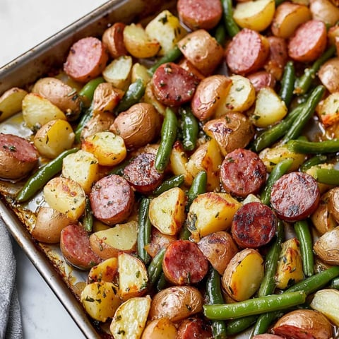 A pan of food with potatoes, green beans, and sausage.