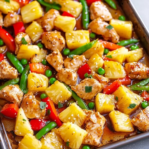 A pan of food with pineapple, peas, and chicken.