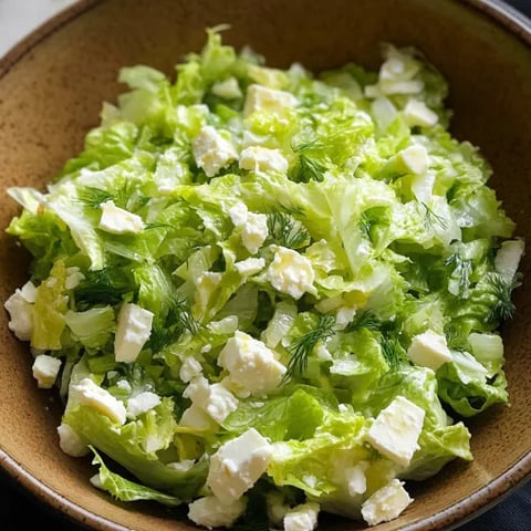 A bowl of salad with lettuce and cheese.