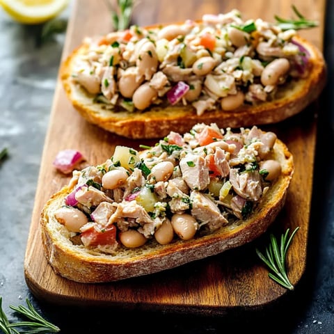 Two slices of bread with meat and beans on them.