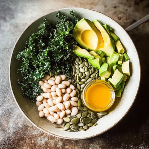 A bowl of food with avocado, beans, and kale.