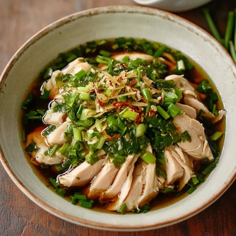 A bowl of soup with chicken and green onions.
