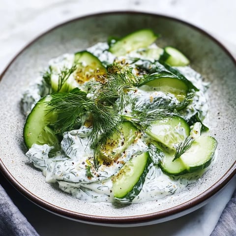 A bowl of cucumber dip with a sprig of parsley on top.