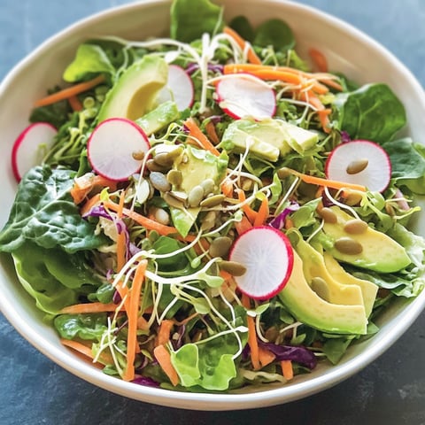 A bowl of California Chef's Salad, featuring a mix of vegetables and seeds, is displayed on a table.