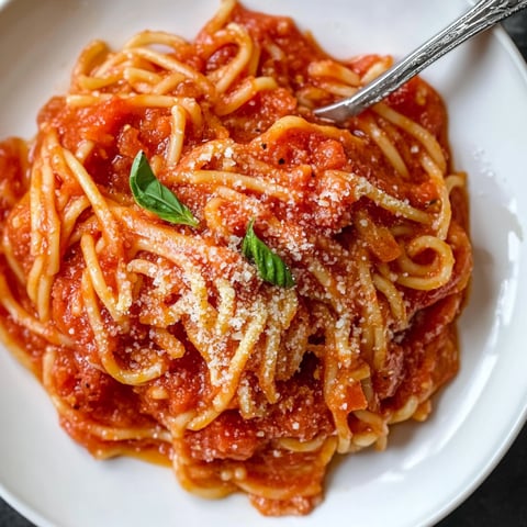 A plate of spaghetti with tomato sauce and cheese on top.