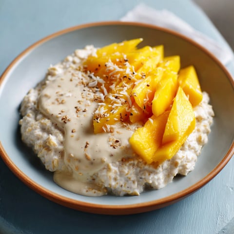A bowl of Mango Sticky Oatmeal with a spoon in it.