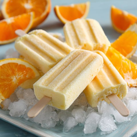 A plate of orange Julius bars with a scoop of ice cream and orange slices.