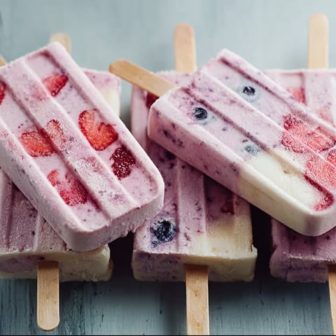 A close up of a delicious yogurt popsicle with blueberries and strawberries.