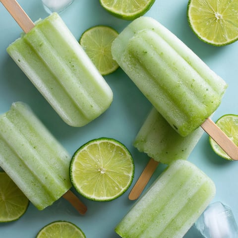 A close up of a lime popsicle with a lime wedge on top.