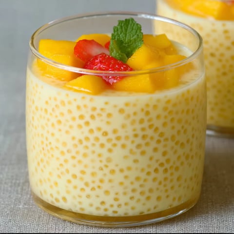 A glass of Mango Tapioca Pudding with a strawberry on top.