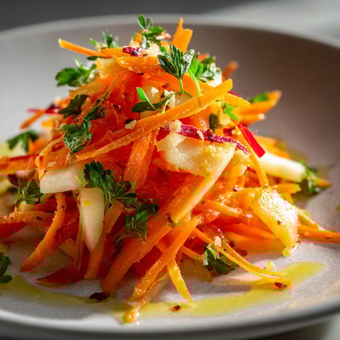A plate of carrot apple salad with a drizzle of olive oil.