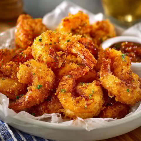 A plate of Southern Fried Shrimp with a dipping sauce.