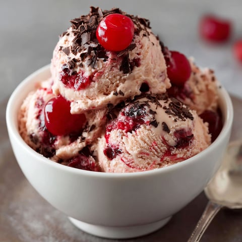 A bowl of Cherry Coke Ice Cream with chocolate chips and cherries on top.