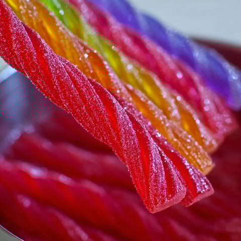 A bowl of Kool Aid Licorice Ropes with a spoon in it.