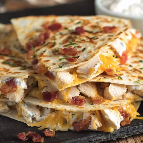 A delicious Chicken Bacon Ranch Quesadilla is stacked on a plate.