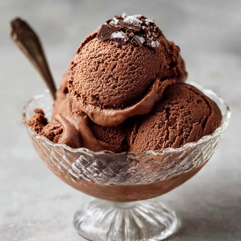 A glass bowl filled with a rich, creamy chocolate ice cream.