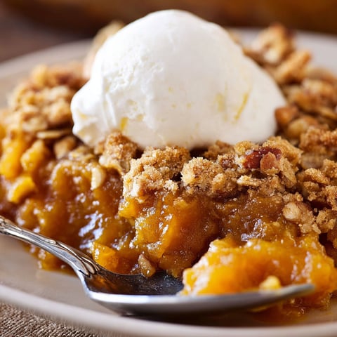 A delicious dessert, Pumpkin Crisp, is served with a scoop of ice cream on top.