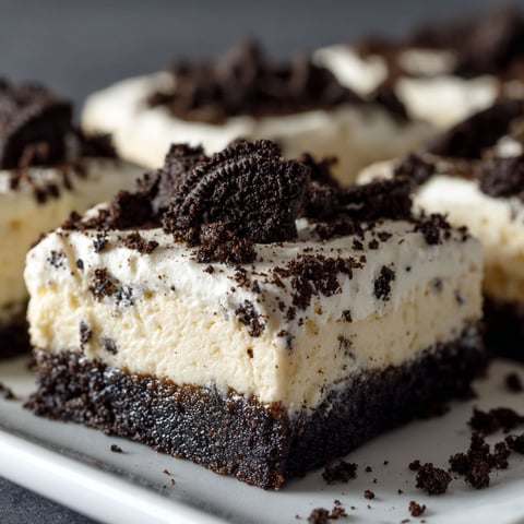 A plate of No-Bake Oreo Cheesecake Bars with chocolate and white toppings.