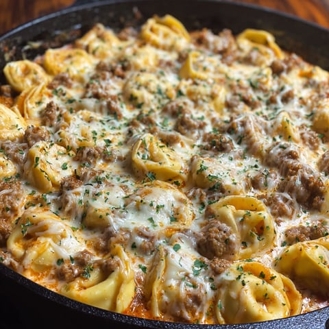 A delicious Creamy Italian Sausage Tortellini dish, cooked in a skillet and ready to be served.