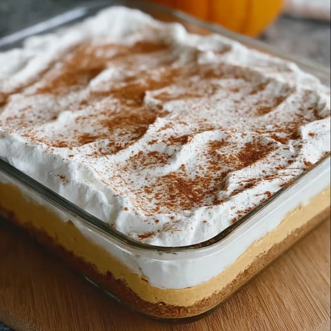 A delicious dessert, Pumpkin Cheesecake Delight, is displayed in a glass pan.