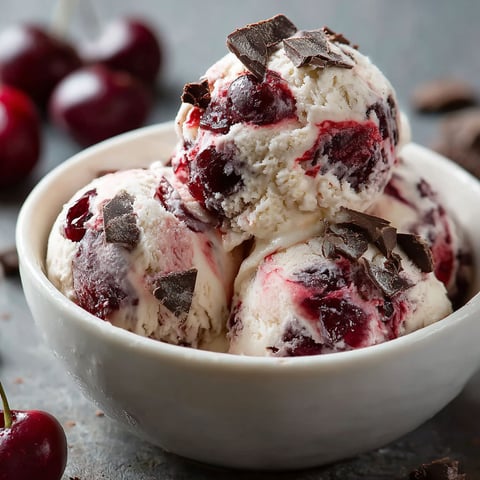 A bowl of Creamy Cherry Garcia Ice Cream with cherries on top.