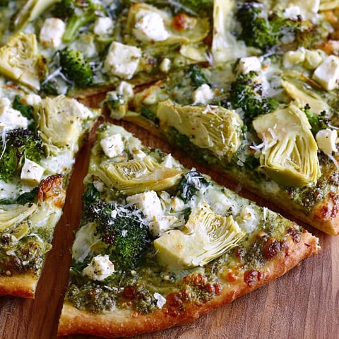 A slice of pizza with broccoli, artichokes, and feta cheese on a wooden table.