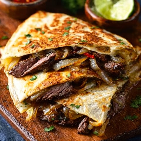 A delicious Steak Fajita Quesadilla is stacked with onions and meat, ready to be served.