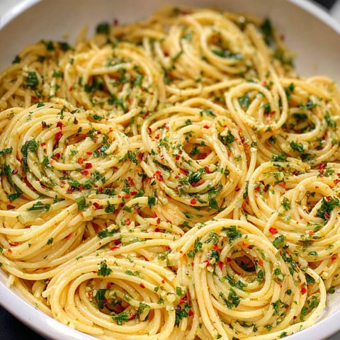A bowl of Spaghetti Aglio e Olio, a popular Italian dish, is filled with noodles and fresh herbs.