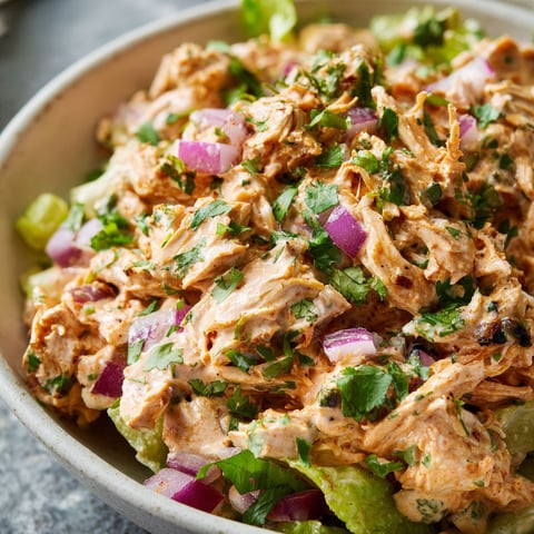 A bowl of Chipotle Chicken Salad, topped with onions and cilantro, is ready to be enjoyed.