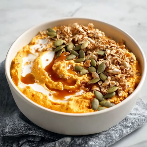 A bowl of pumpkin whipped cottage cheese breakfast is topped with nuts and seeds.