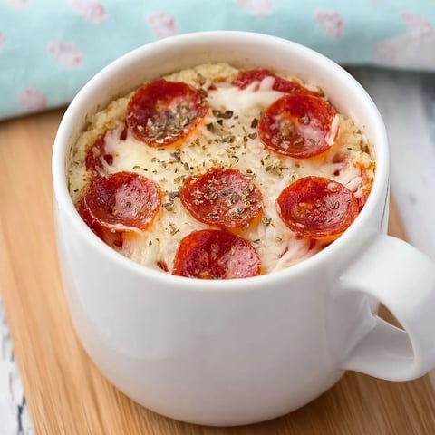 A cup of pizza with pepperoni and cheese in it.