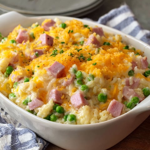 A delicious casserole with ham and peas in a white bowl.