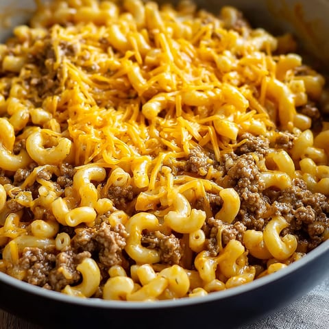 A bowl of macaroni and cheese with hamburger meat on top.